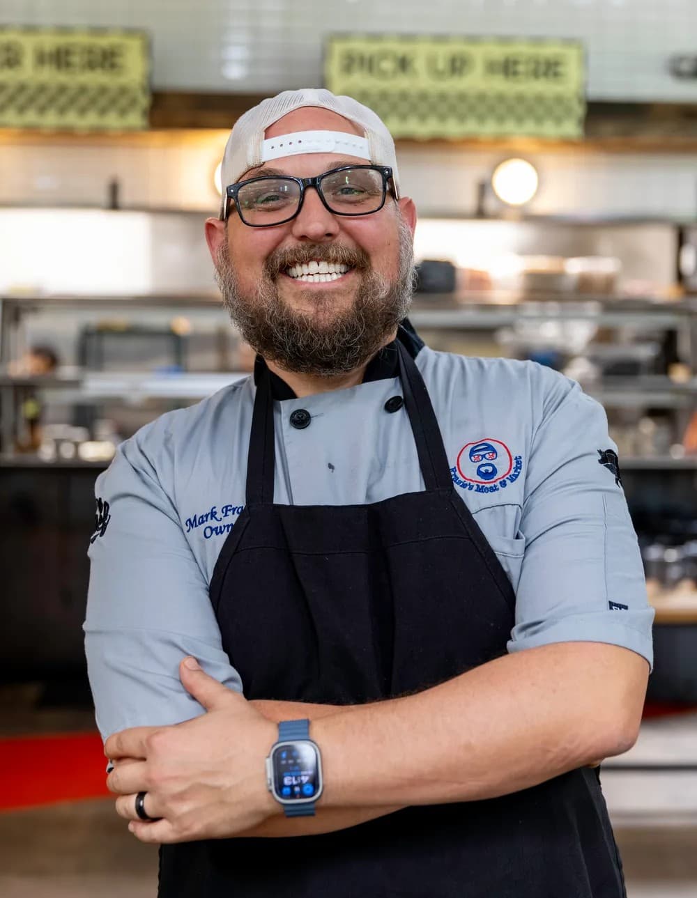 Mark Frazie wearing a chef's coat and apron at Frazie's Meat and Market
